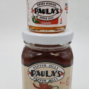 1.7 oz. jalapeno pepper jelly jar full of jelly on top of the 8 oz. Paula’s Pepper Jelly jar filled with jelly.