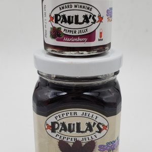 The 1.7 oz. marionberry pepper jelly jar on top of the 8 oz. Paula’s Pepper Jelly jar both full of marionberry pepper jelly.